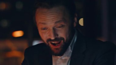 Portre neşeli yönetmen karanlık ofisten arıyor. Bilgisayarla konuşan gülümseyen adam web kamerasıyla duygularını paylaşıyor. Kahkaha Yöneticisi uzak kabinede online konferansın keyfini çıkarıyor