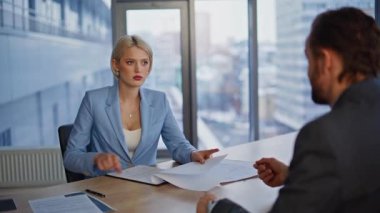 Girişim kurucusu, yatırımcıyla iş yerinde sıkı sıkıya selamlaşma anlaşmasını sonuçlandırıyor. Gülümseyen yönetici onaylayan belge, iş birliğinden memnun. Takım arkadaşları işbirliği düzenliyor