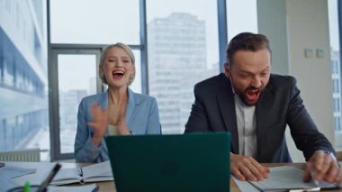 Duygusal partnerler modern ofiste beş başarı elde etmenin keyfini çıkarıyorlar. Hafif iş yerinde iş başarısını kutlayan mutlu iki meslektaşım. Heyecanlı iş arkadaşları dizüstü bilgisayara bakıp kağıtları fırlatıyorlar 