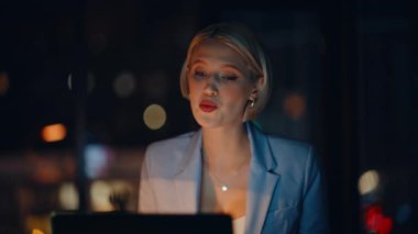 Gülümseyen iş kadını bilgisayarını kullanarak gece ofisini arıyor modern iş merkezini kapatıyor. İnternetteki konferansta geç saatlere kadar çalışan biri konuşuyor. Pozitif kadın danışman iş görüşmesi hakkında konuşuyor