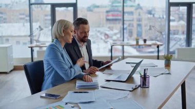 Modern panoramik çalışma alanında bilgisayar ekranını uzaktan izleyen üretken iş arkadaşları. Neşeli ekip üyeleri yeni proje stratejisini analiz ediyor. Açık kabine ortamında online oturum yapıyorlar.