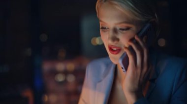 İş kadını elleri şirket ofisinde dizüstü bilgisayara dokunuyor. Sarışın kadın cep telefonunu arıyor. İş projesinde fazla mesai yapıyor. Gülümseyen işçi gece geç saatlerde akıllı telefondan konuşuyor.