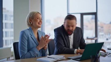 Heyecanlı ortaklar, hafif ofisteki dizüstü bilgisayarlı ekranda sevinçten havalara uçuyor. Cam duvar işyerinde iş başarısını kutlayan mutlu iki meslektaşım. Duygusal iş arkadaşları beş kişiye başarıyı tattırıyor