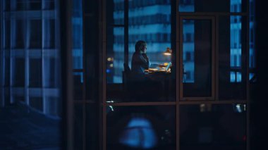 Siluet lideri gece vakti iç pencere görüntüsü ile konuşuyor. Ofis çalışanı şehir binalarında el kol hareketi yapıyor. Pozitif yönetici konuşması cep telefonu iş başarısını tartışıyor