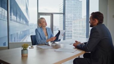 Müstakbel iş ortakları yakın planda oturarak sözleşme imzalıyor. İş kadını işadamı el sıkışıyor ve anlaşma yapıyor. İki kendine güvenen yatırımcı iş toplantısında ayrıntıları tartışırken ortaklıktan keyif alıyor 