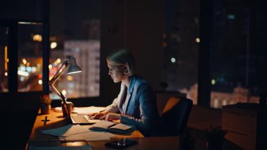 Aşırı mutlu broker dizüstü bilgisayar görünümlü gece işyerinde harika haberler okuyor. Heyecanlı iş kadını akşam ofisinde online zaferi kutluyor. Mutlu bir kadın para kazanmaya başlar. El kol hareketi yapar. 