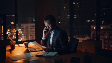 Akşam iş adamı, cep telefonu danışmanlığını arıyor. Birden fazla görev yöneticisi masa başında dizüstü bilgisayarı kontrol ediyor. İdari tartışmacı proje akıllı telefonu çevrimiçi 