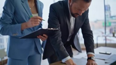 Kapanış ekibi ofis masasında belgeleri analiz ediyor. Endişeli meslektaşlar iş yerindeki beyin fırtınalarını tartışan kağıtları gözden geçiriyorlar. Toplantıda dizüstü bilgisayar kullanan profesyonel iş arkadaşları 