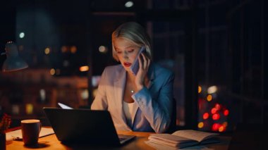 Çok çalışan sarışınlar cep telefonu konuşarak bilgisayar masasının yakınındaki belgeleri araştırıyorlar. Stresli bir kadın akıllı telefonu arayıp karanlık dairede proje sorunlarını tartışıyor. CEO akşam haberleşecek.