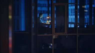 Gece vardiyası sırasında cam duvar manzaralı bir bilgisayar. Ofis uzmanı online araştırma projesini geç bitirmeye odaklanmış. Anonim işçi fazla mesai yapıyor. Sessiz çalışma alanı. Kurumsal yalnızlık