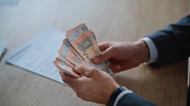 Direktör parmaklarını zarif çalışma alanlarında yakın planda tutuyor. Zengin bir girişimci masanın karşısındaki kadın ortağa fatura dağıtıyor. Gizemli yatırımcı, gizli işlemi sessizce tamamlıyor.