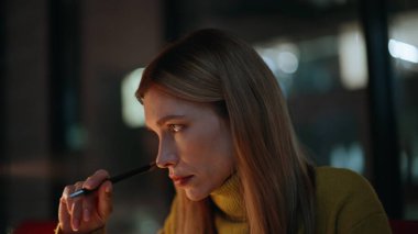 Öğrenci projesi gece apartmanında. Yakın plan. Düşünceli kadın yazar, karanlık işyerinde kalem üzerinde kafa yoran fikirler tutuyor. Düşünceli iş kadını gece geç saatlere kadar çalışıyor. Yorgun hissediyor..