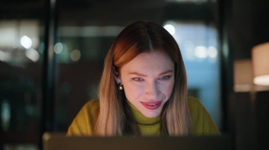 Gülümseyen programcı dizüstü bilgisayarı karanlık çalışma alanına yakın oturuyor. Gece işyerinde bilgisayardan e-posta okuyan mutlu bir iş kadını. Memnun kadın yönetici fazla mesai yaparak başarıyı düşünüyor..