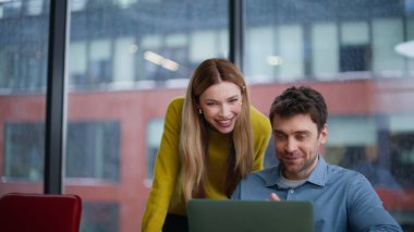 Ofiste laptoptan iki iş arkadaşı görüntüsü var. Çevrimiçi konferansta bilgisayar kamerasına gülümseyen iş arkadaşları proje sunuyor. Mutlu ortaklar takımı internet toplantısını tartışıyor.