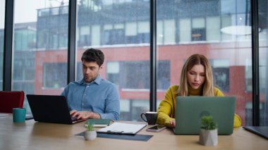 Ciddi girişimciler panoramik pencereli ofis konferans odasında proje üzerinde çalışıyor. Dizüstü bilgisayar yazmakla meşgul iki yönetici aşırı yüklenmiş hissediyor. İşletme görevlerini birlikte çözmeye odaklanmış meslektaşlar.