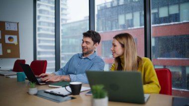 Gülümseyen yönetici kadın meslektaşına projeyi açıklarken dizüstü bilgisayarları yakın plan çekiyorlar. İş yerindeki iş arkadaşlarımız panoramik pencerede fikir alışverişinde bulunuyor. Pozitif takım değişim deneyimleri.