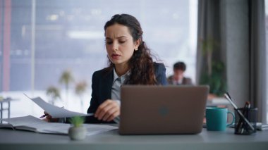 Şirket işyerindeki belgeleri inceleyen kaş çatık kaşlı bir kadın. Elinde kağıtlar tutan iş kadını hata buldu. Stresli yönetici