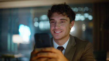 İşadamı gece ofisinde tatmin olmuş bir portre mesajı alıyor. Karanlık iş yerinde cep telefonu mesajlarını okuyan mutlu yöneticiler.