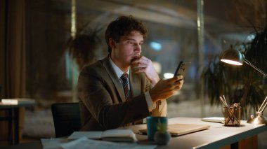 Karanlık bir iş yerinde rahat bir yönetici cep telefonuna göz atıyor. Gülümseyen işadamı gece ofisinde akıllı telefon mesajı okuyor. Konuşan adam.