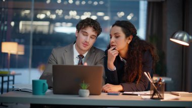 Gece vardiyasında bilgisayar ekranına bakan gece işçileri. Flört eden adam yöneticisi karanlık işyerindeki sekreter kadına projeyi açıklıyor