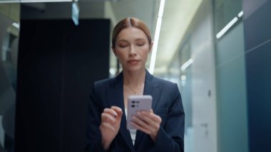 Gülümseyen yönetici kadın cep telefonunu kullanarak koridoru tek başına kapatıyor. Gülümseyen iş kadını iş arkadaşlarını selamlıyor cep telefonuna mesaj atıyor. Olumlu kadın yönetmen toplantıdan önce dinleniyor.