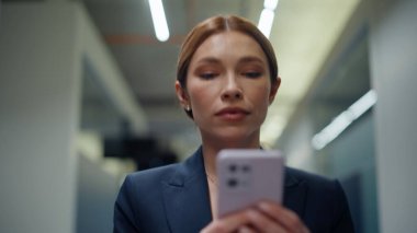 İş kadınının portresi. Ofis koridorunda akıllı telefon mesajı. Gülümseyen yönetici kadın elleri boş koridorda cep telefonuna bakıyor. Başarılı iş sahibi cep telefonu kullanarak e- posta gönderiyor