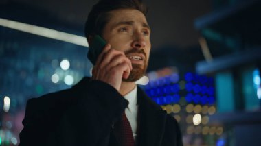 Hüsrana uğramış patron gece şehir manzaralı portrede cep telefonundan şikayetçi. Üzgün sakallı adam, şehir merkezinde akıllı telefondan konuşuyor. Endişeli işadamı iş hayatı sorunlarını internette paylaşıyor
