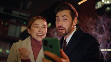Heyecanlı iş çifti akşam üzeri cep telefonlarını arıyor. Karanlık modern bölgede başarılı olan gece iş arkadaşları akıllı telefon ekranlarını izliyorlar. Neşeli yeni başlayanlar 