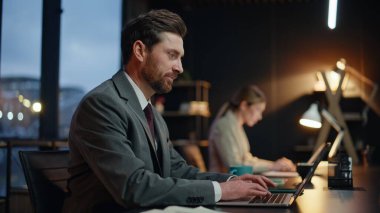 İş adamları geç saatlere kadar çalışıp şirket ofisindeki bilgisayarlara mesaj atıyorlar. Modern çalışma alanında karşılıklı gülümseyen pozitif görünümlü bir iş kadını. Profesyonel iş arkadaşlarının teslim tarihi var.