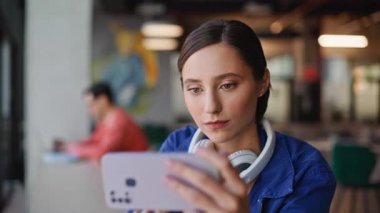 Freelancer cep telefonunda video izleyip modern restoranı kapatıyor. Gülümseyen kadın yatay cep telefonunda çevrimiçi içeriğe göz atıyor. Akıllı telefonu olan mutlu kız öğrenci sosyal medyadan keyif alıyor..