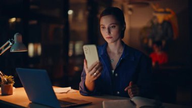 Karanlık iş yerinde cep telefonu mesajlarına göz atan neşeli bir öğrenci. Mutlu iş kadını ofis lambası ışığında internet iletişiminin tadını çıkarıyor. Güzel kadın yönetici akıllı telefon mesajı okuyor..