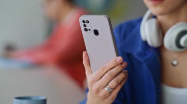 Modern şehir kafeteryasında cep telefonu hippilerin elinde. Boynunda kulaklığı olan genç bir kadın küçük bir restoranda cep telefonu mesajı okuyor. Mavi gömlekli bir kız akıllı telefon uygulamasına bakıyor..