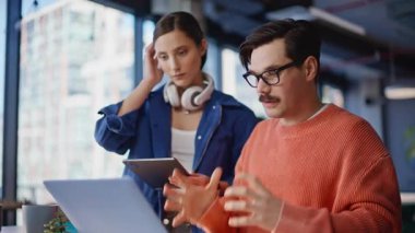 Stresli iş adamları iş yerindeki iş yerlerinin yakınlaşmasını videoya çekiyor. Sinirli adam bilgisayarını kapatıp tablet tutan endişeli kadına bakıyor. Endişeli yöneticiler iş yerinde online toplantı yapmaktan bıktılar.