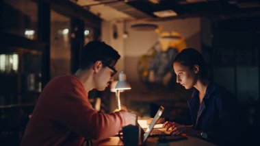 Başarılı iş arkadaşları gece ofisindeki dizüstü bilgisayarlarla kazanmanın keyfini çıkarıyorlar. İki geç çalışan, e-posta okuyarak iş başarısını kutluyorlar. Coşkulu iş arkadaşları akşamları beş tatmin edici takım çalışması yapıyor.