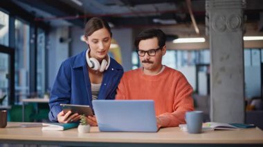 Şirket personeli çevrimiçi proje yakın planında iş birliği yapıyor. Gülümseyen kadın tabletteki verileri kontrol ediyor bıyıklı adamla konuşuyor. İki meslektaşım birlikte yaratıcı bir girişim üzerinde çalışıyor..