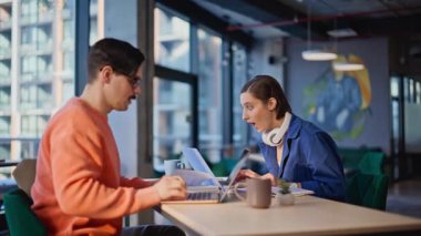 Heyecanlı yeni başlayanlar ofisin açık alanındaki başarılarını kutluyorlar. İki mutlu galip beş başarılı proje veriyor. Duygusal meslektaşlar laptopta harika haberlere içeriden tepki veriyorlar.