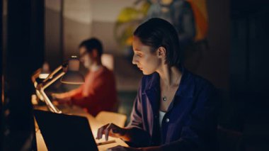 İki serbest çalışan gece lamba ışığında iş yerini paylaştılar. Bilgisayarda yazı yazan ciddi bir kadın akşam üstü internette araştırma yapıyor. Takım yöneticileri, karanlık iş yerinde son teslim tarihine aşırı yükleme yaptılar..