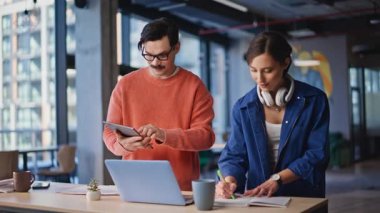 Finans şirketinin çalışma alanına dizüstü bilgisayar araştırması yapmayı planlayan profesyonel iş arkadaşları. İki başarılı meslektaşımız projeyi tartışıyor. İş ekibi tablet yazma notlarındaki verileri kontrol ediyor.