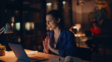 Gece mesai saatinde serbest çalışan mutlu videolar. Gülümseyen iş kadını çevrimiçi toplantı düzenliyor ve not defterine not alıyor. Ofisteki sanal konferansta konuşan gülen kadın..