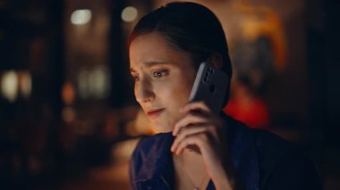 Stresli bir çalışan, gece mesai saatinde akıllı telefondan konuşuyor. Endişeli kadın yönetici cep telefonuyla yazılım sorunundan şikayet ediyor. Sinirli iş kadını telefonda başarısızlığı tartışıyor..