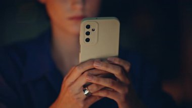 İş kadını elleri, gece ofisinde akıllı telefondan mesaj atıyor. Gece geç saatlerde cep telefonu mesajı gönderen ciddi bir serbest çalışan kadın. Şirket çalışanı karanlık çalışma alanında telefon internet uygulamasına göz atıyor.