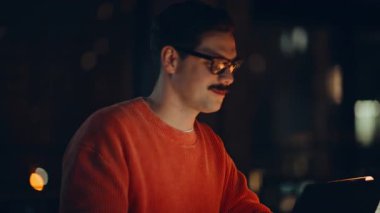 Gece işyerinde gülümseyen adam konuşuyor. Yakın plan. İki acemi, karanlık işyerindeki iş belgelerini inceliyor. Finansal belgeleri lamba ışığında inceleyen profesyonel girişimciler.