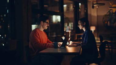 Ofis ekibi laptoplara odaklandı. Karanlık çalışma alanındaki bıyıklı iş adamına mali rapor sunan ciddi bir kadın. İki muhasebeci gece geç saatlerde iş belgelerini inceliyor..