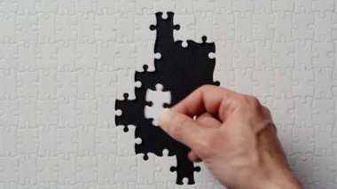 Parmaklar yapboz parçasını siyah yakın plan üzerine yerleştiriyor. Bulmaca çözümü. Hedefe ulaşılıyor. Net görüş projesi sonucu. Analitik düşünme tekniği. Formasyon geliştirme fikri