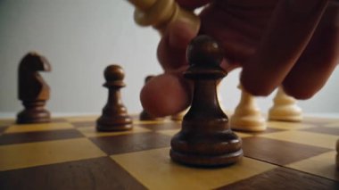 Satranç tahtasındaki kahverengi piyon taşını hareket ettiren adamın yakın çekimi. Mantık oyunu oynayan biri. Savaş alanındaki parmak kaldırma birimi farklı figürlerle dolu. Liderlik ve iş stratejisi kavramı 