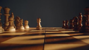 Satranç tahtasında ilk el hareketini kapalı mekanda yapıyor. Bilinmeyen oyuncu kahverengi piyonu hareket ettiriyor ve yarışmanın tadını çıkarıyor. Oyuncu parmaklarını kareli ızgarada oynatıyor. Tahta oyunu ve strateji geliştirme 