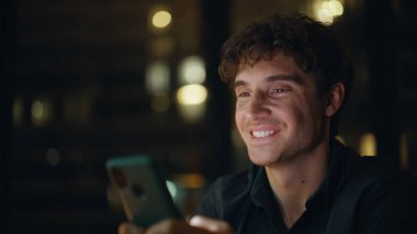 Geceleri cep telefonuna mesaj atan gülümseyen bir adam. Mutlu erkek serbest çalışan akıllı telefonlu mesaj gecenin geç saatlerinde internet iletişiminin keyfini çıkar. Ofiste cep telefonu ekranını dinleyen işadamı elleri