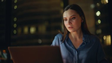 Karanlık ofis kapanışında dizüstü bilgisayarında harika haberler okuyan başarılı bir girişimci kadın. Para geliri konusunda şaşırmış bir iş kadını. Duygusal bayan heyecan duyuyor. Kapalı alanda bilgisayar çalışıyor..