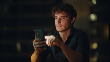 Neşeli, serbest çalışan, gece iş yerinde cep telefonuna göz atan biri. Gülümseyen yönetici cep telefonundan iş teklifini okuyordu. Akıllı telefondan online alışveriş yapan mutlu iş adamı.