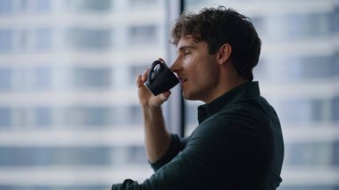 İş yerinde espresso içen kendine güvenen işadamı başarıyı yakından düşünüyor. Yakışıklı bir işletmeci, bilgisayarla kahve molası verip ofis masasına oturuyor. Başarılı yönetici düşünceleri..